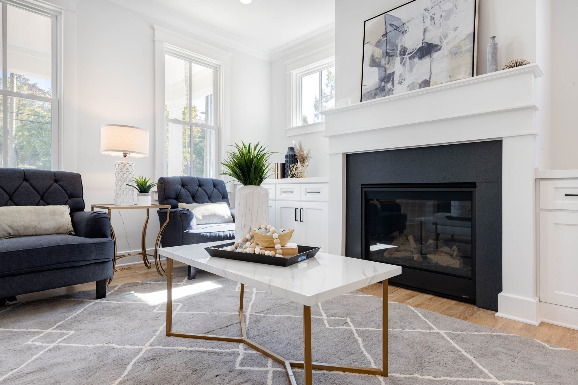 A bright white living room with a cozy and inviting fireplace, with a white marble and gold coffee table highlighting luxury real estate photography in Durham, North Carolina